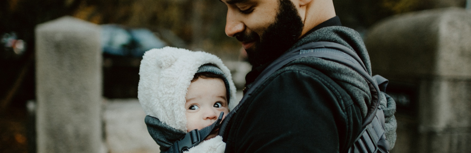 bearded father wears baby in a carrier