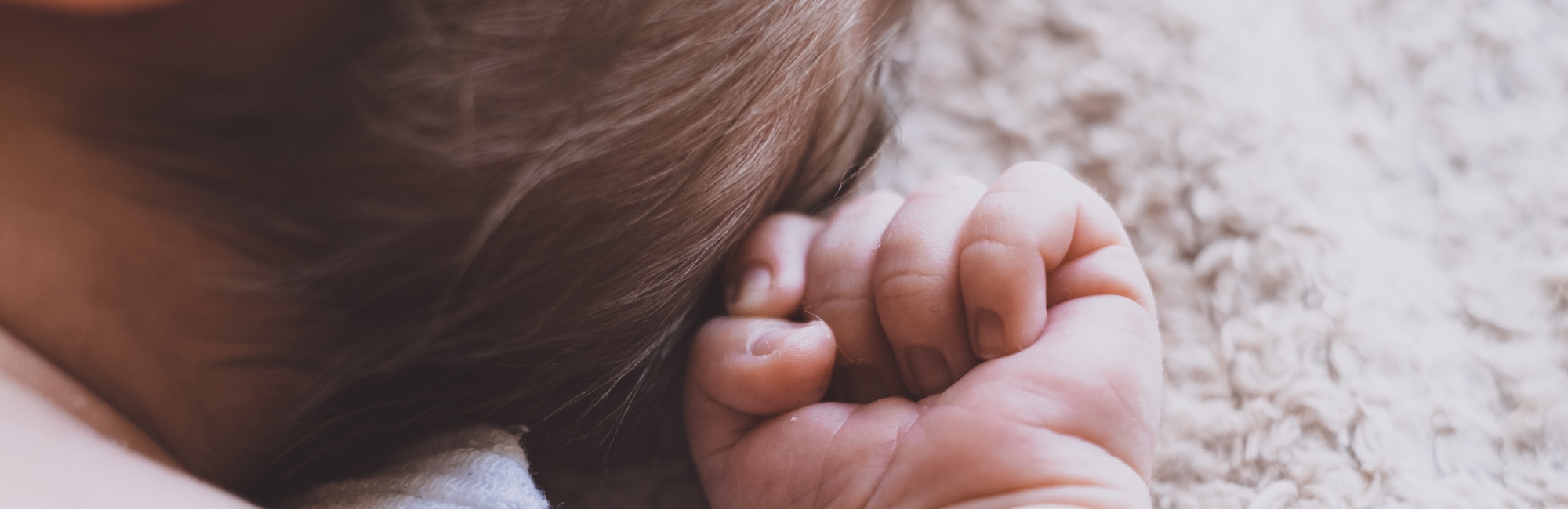 baby with clenched hand laying in daylight