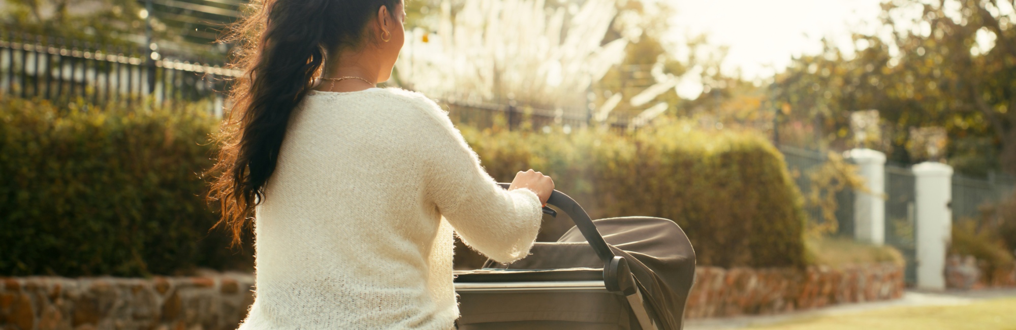 mother walks outside down footpath pushing pram