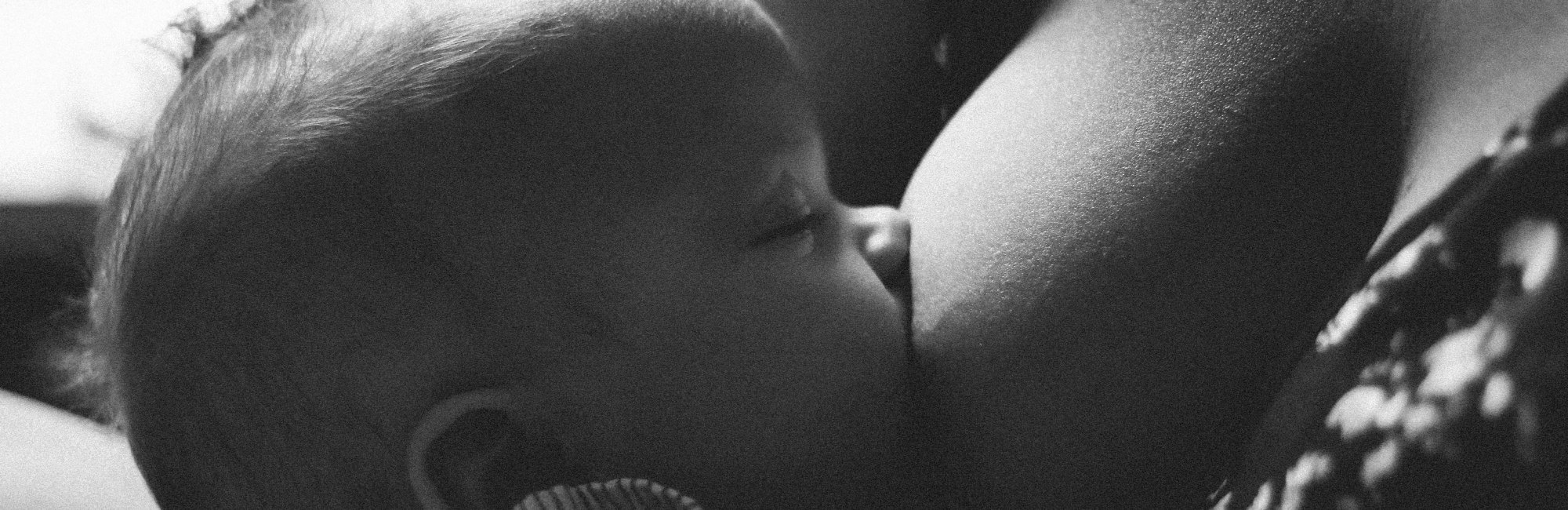 black and white photo of baby breastfeeding