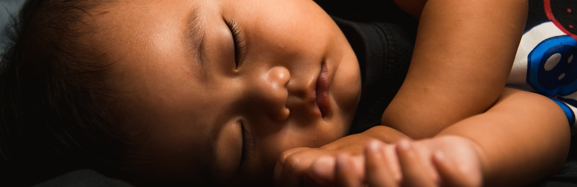 brown skinned child sleeping on its side