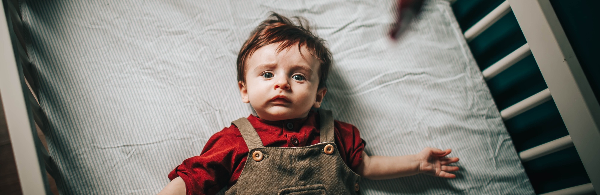 baby lying on back in a cot during the daytime