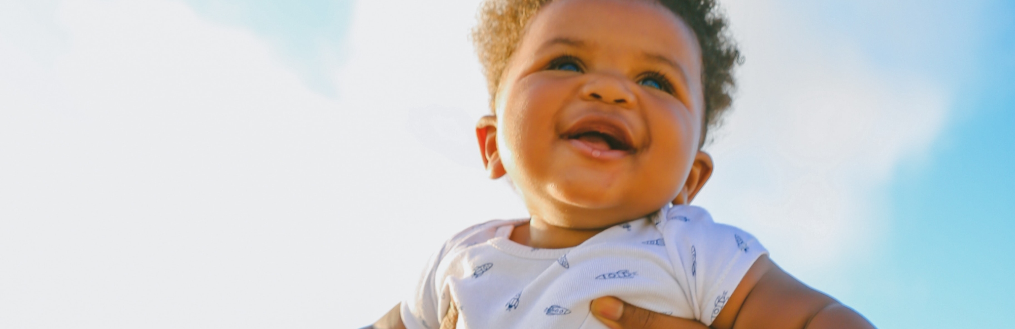 Black baby being held up in sky