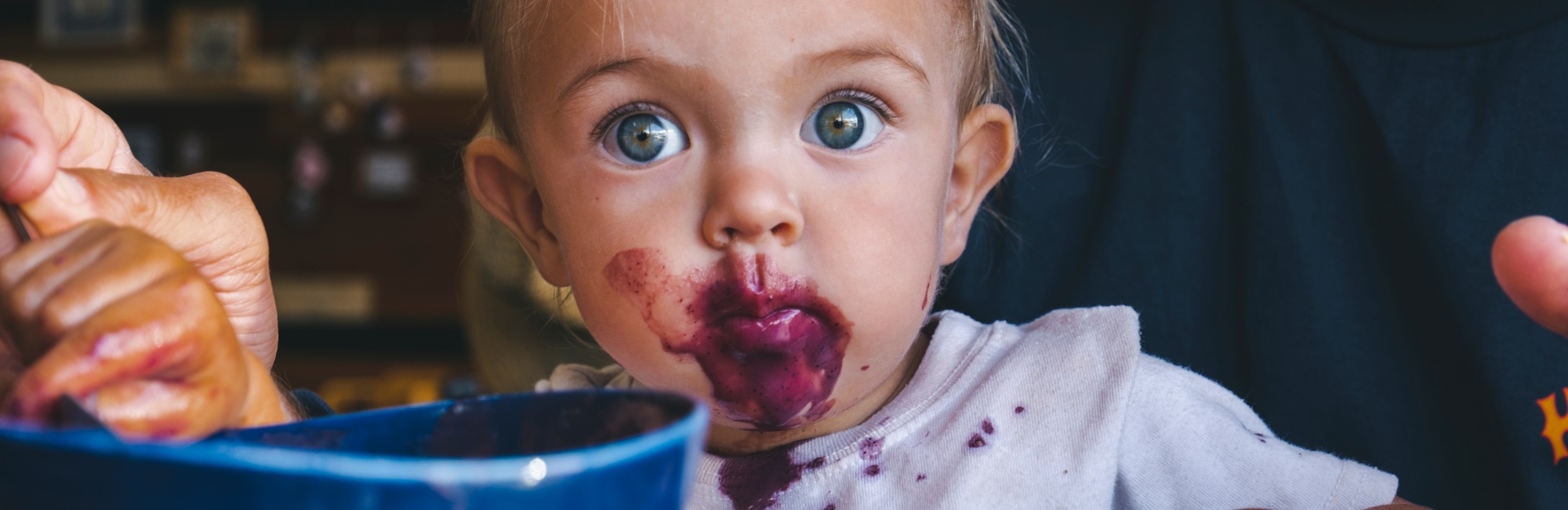 wide eyed toddler covered in berry juice
