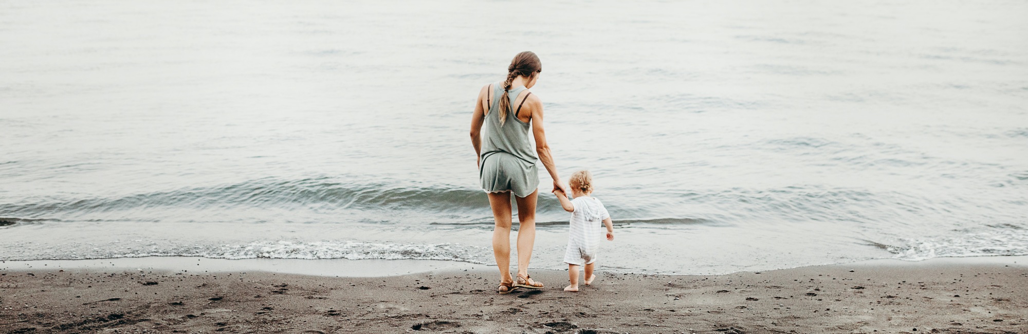 mother and toddler playing by ocean
