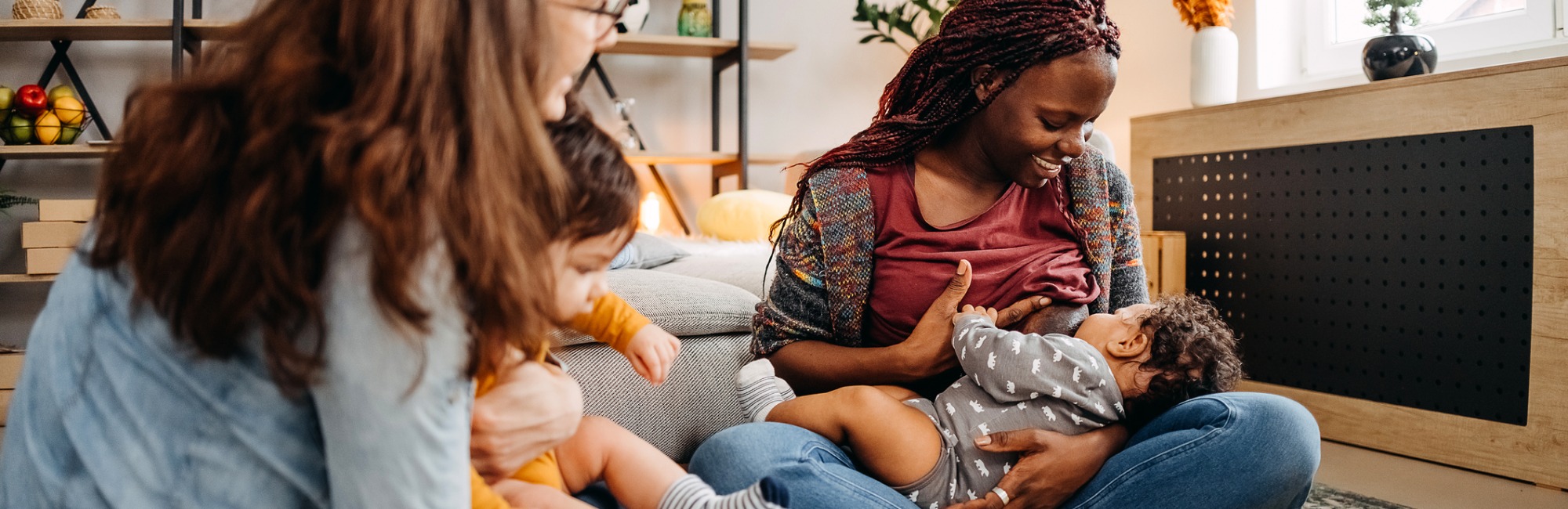 mothers and their babies sit in circle, one mother breastfeeds