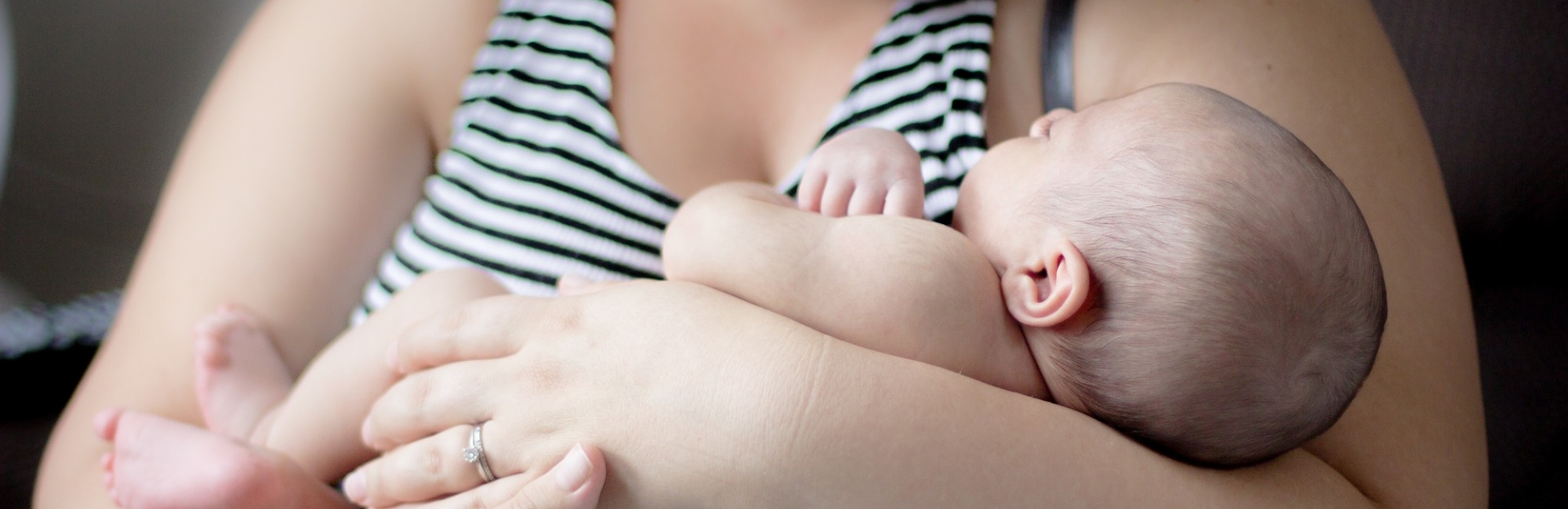 baby sleeping while being held in mother's arms