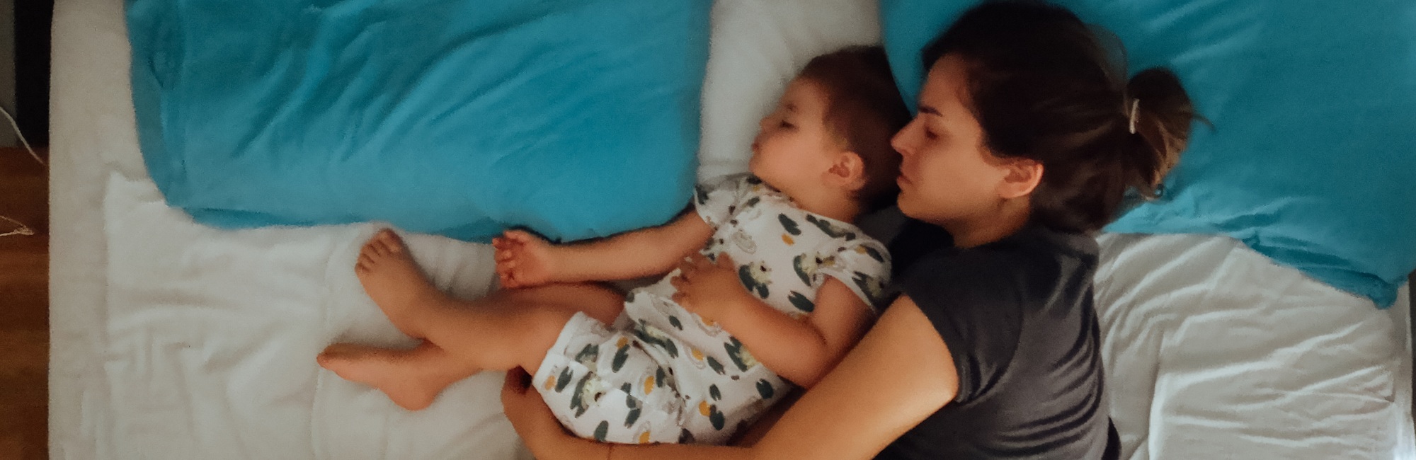 mother and child cuddle as they sleep in bed