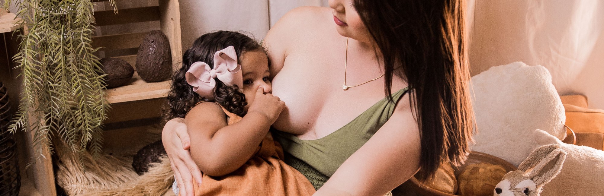 young child with pink bow in her hair breastfeeding